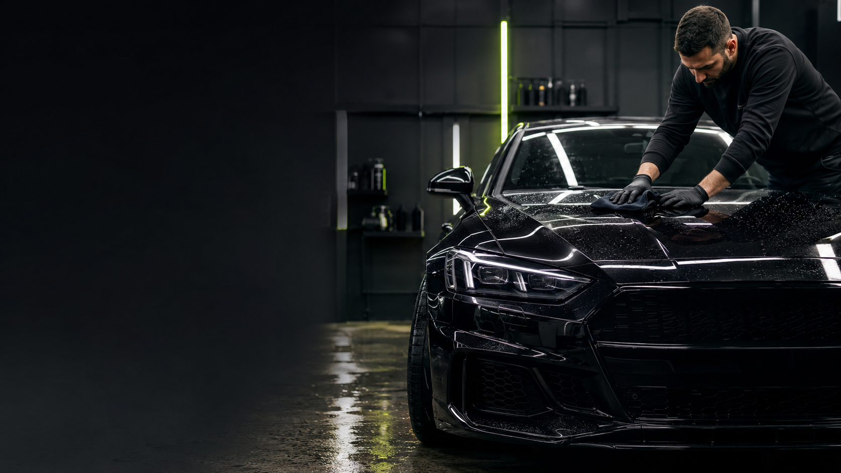 Detailer polishing a black car in a dark studio